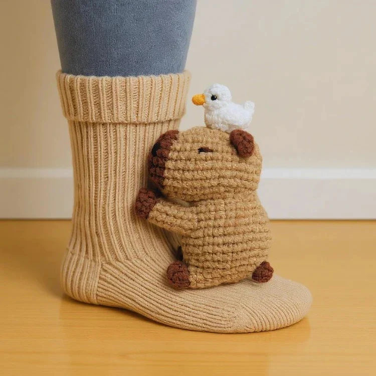 Beige knitted sock with a brown animal design and white bird on top, worn on a foot.